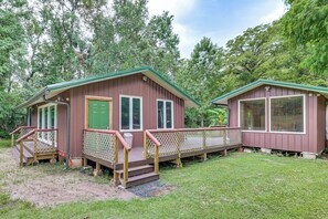 Two cabins with wooden decks and railings, surrounded by a grassy area and trees.