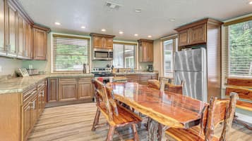 Une cuisine spacieuse dotée de meubles en bois, d’un réfrigérateur en acier inoxydable et d’une grande table à manger avec des chaises.