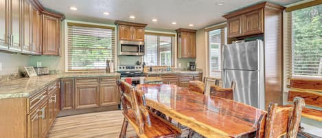 A spacious kitchen with wooden cabinets, a stainless steel refrigerator, and a large dining table with chairs.