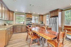 A spacious kitchen with wooden cabinets, a stainless steel refrigerator, and a large dining table with chairs.
