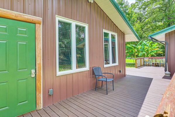 A wooden deck with a green door and two windows.