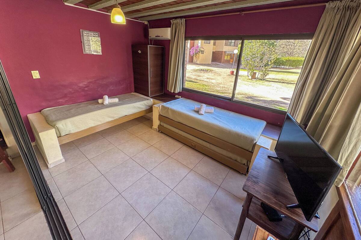 Una habitación con cama, televisión y ventana con cortinas.