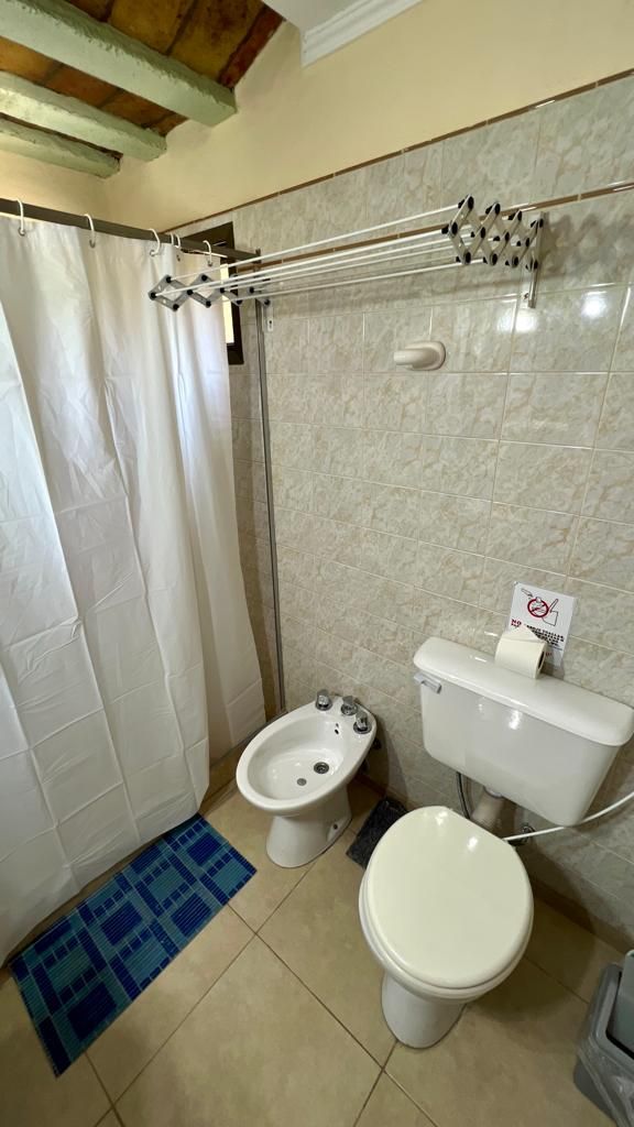 Baño con ducha, inodoro, bidé y perchero para toallas.