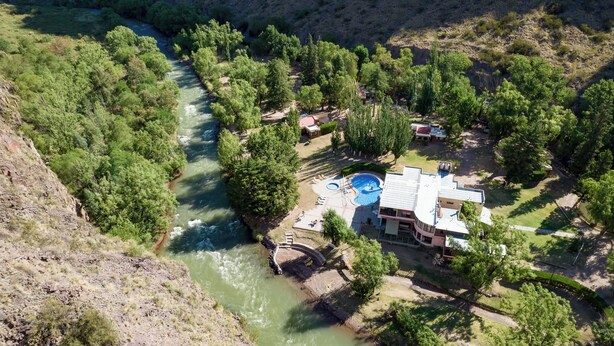 Un complexe hôtelier doté d’une piscine, d’un pont enjambant une rivière et d’une végétation luxuriante.