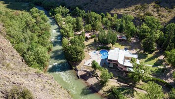 Um resort com piscina, uma ponte sobre um rio e vegetação exuberante.