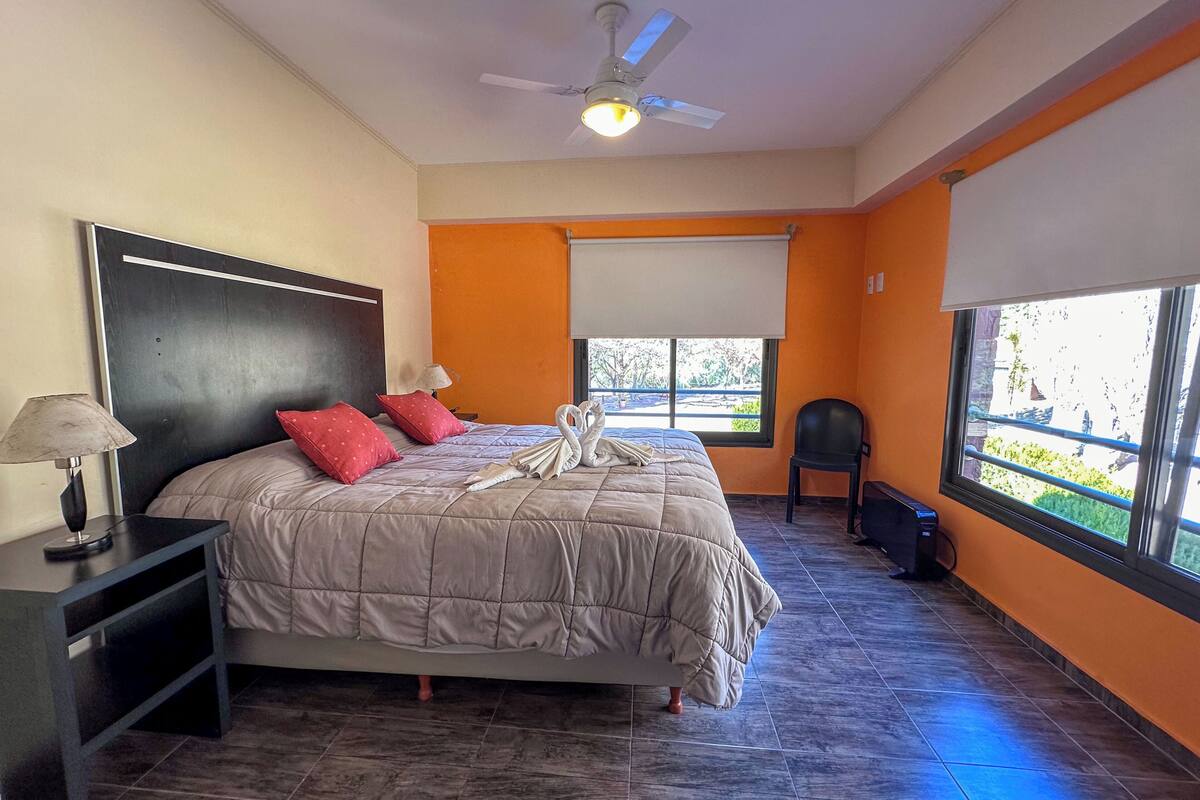 Un dormitorio con cama, mesita de noche, lámpara y ventilador de techo.