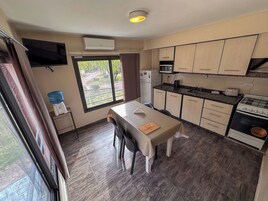 Uma cozinha compacta com área de jantar, dispensador de água, TV e vista para o exterior.