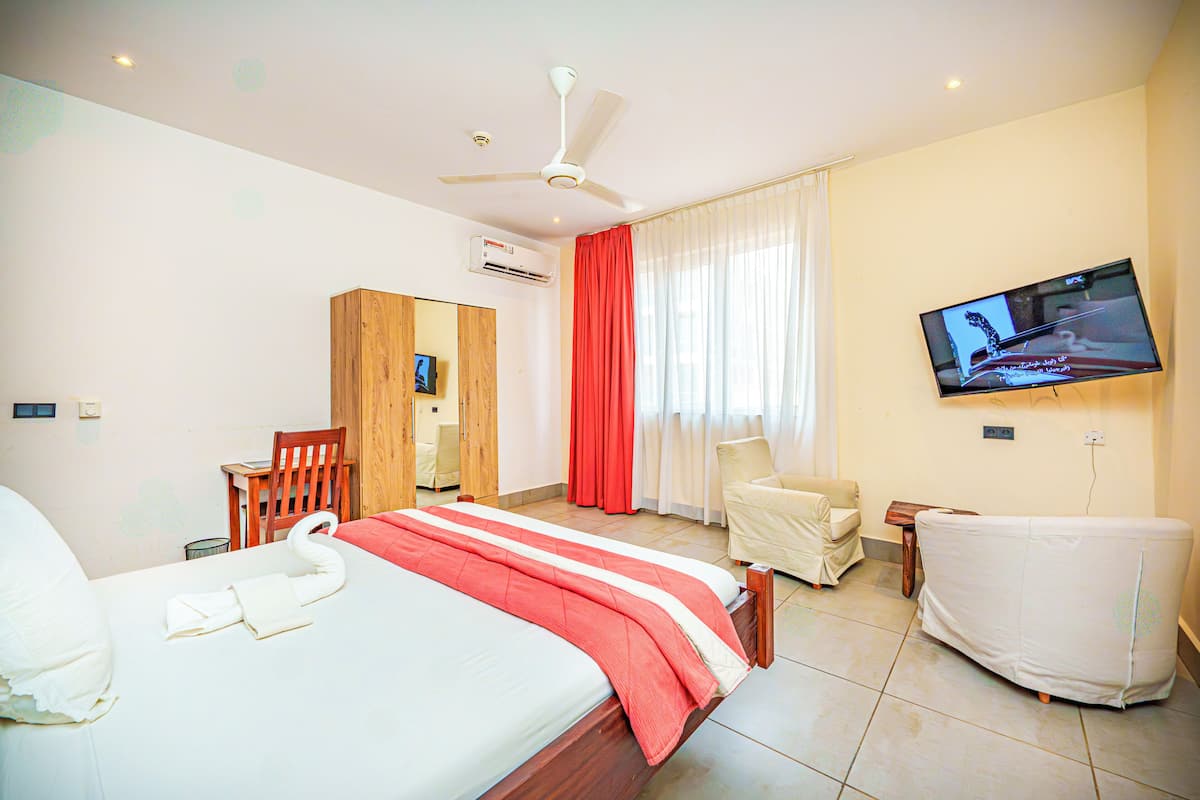 A hotel room with a bed, a TV, a desk, a chair, and a sofa.