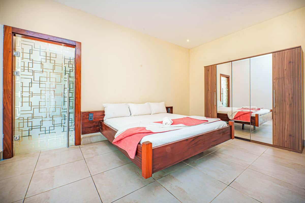 A bedroom with a wooden bed, a mirror cabinet, and a glass door with a geometric pattern.