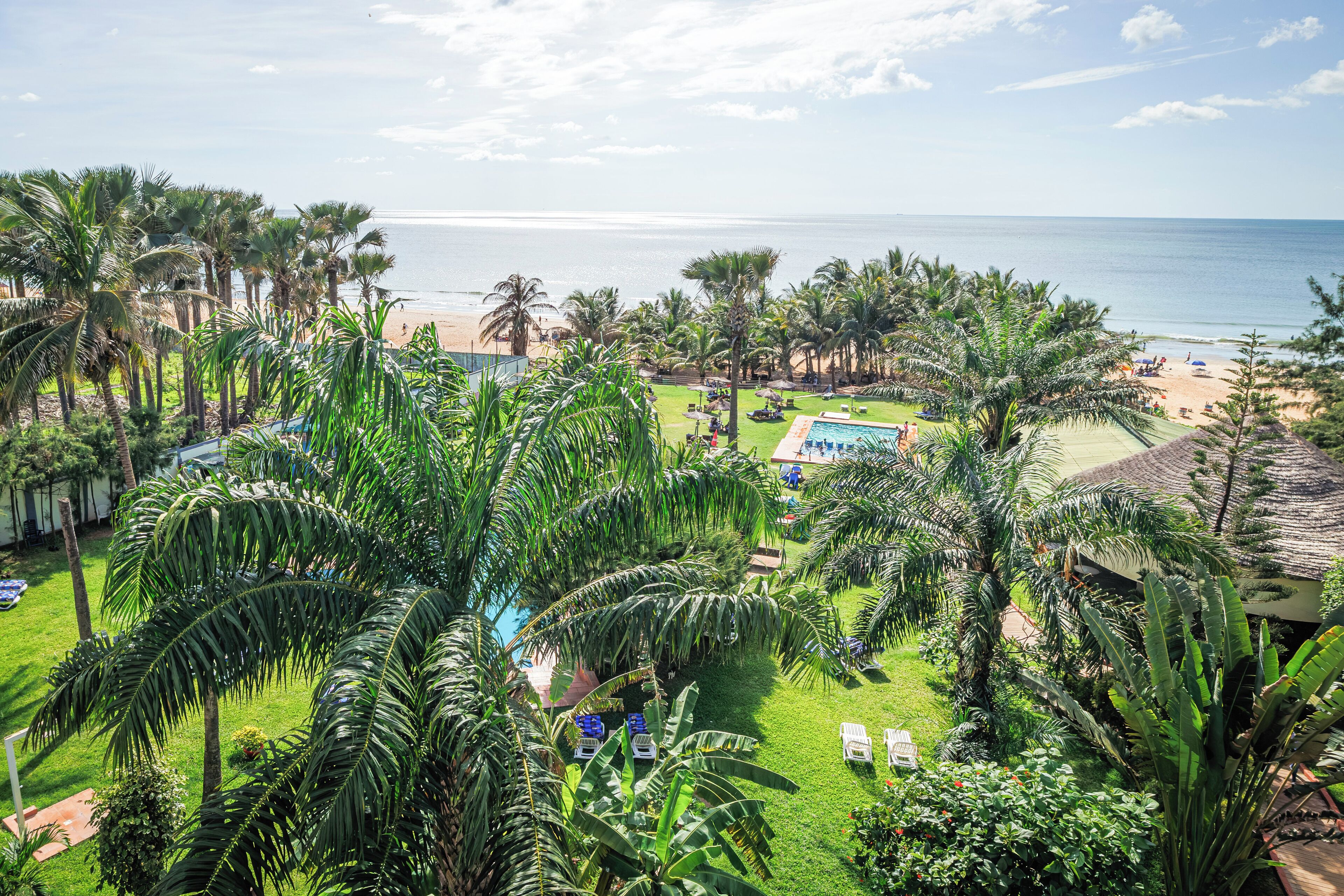 A resort with a pool, palm trees, and a beach view.