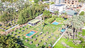 An aerial view of a resort with multiple swimming pools, sun loungers, and palm trees. - Kasumai Beach Resort (Serrekunda)