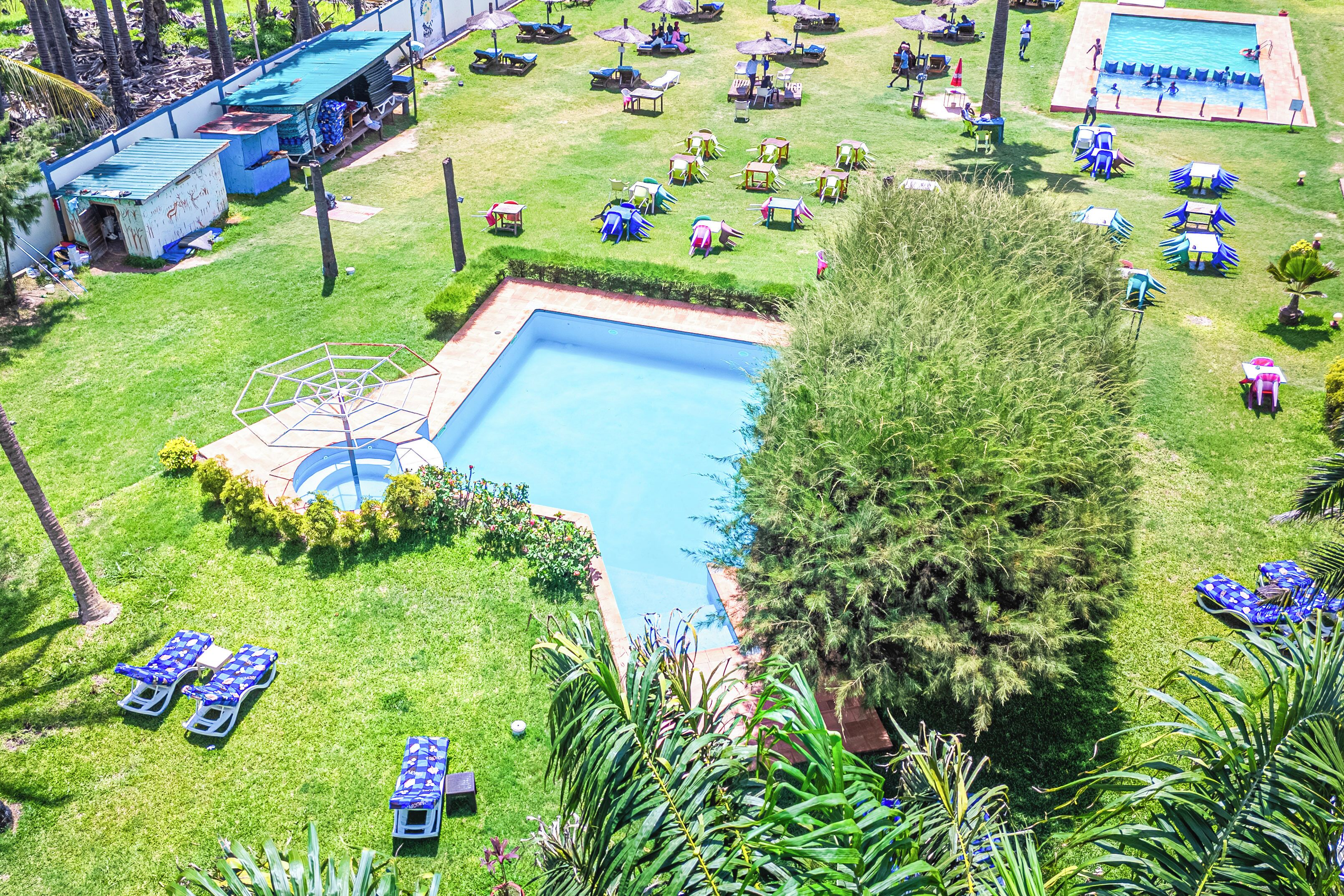 Un área de piscina con varias piscinas, sillas de descanso y sombrillas.