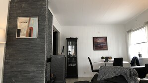 Un salon moderne avec une cheminée, un coin repas avec une table et des chaises, et une cuisine équipée de meubles et d’appareils électroménagers.