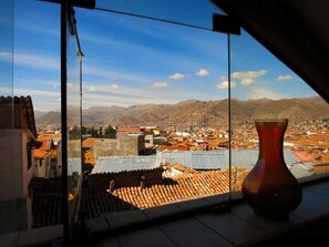 A view from a window overlooking a cityscape with mountains in the background.