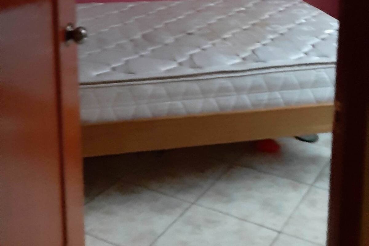 A room with a bed, a door, and a red wall.