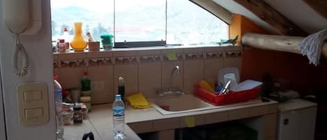 A compact kitchen with a gas stove, a sink, and a small refrigerator.