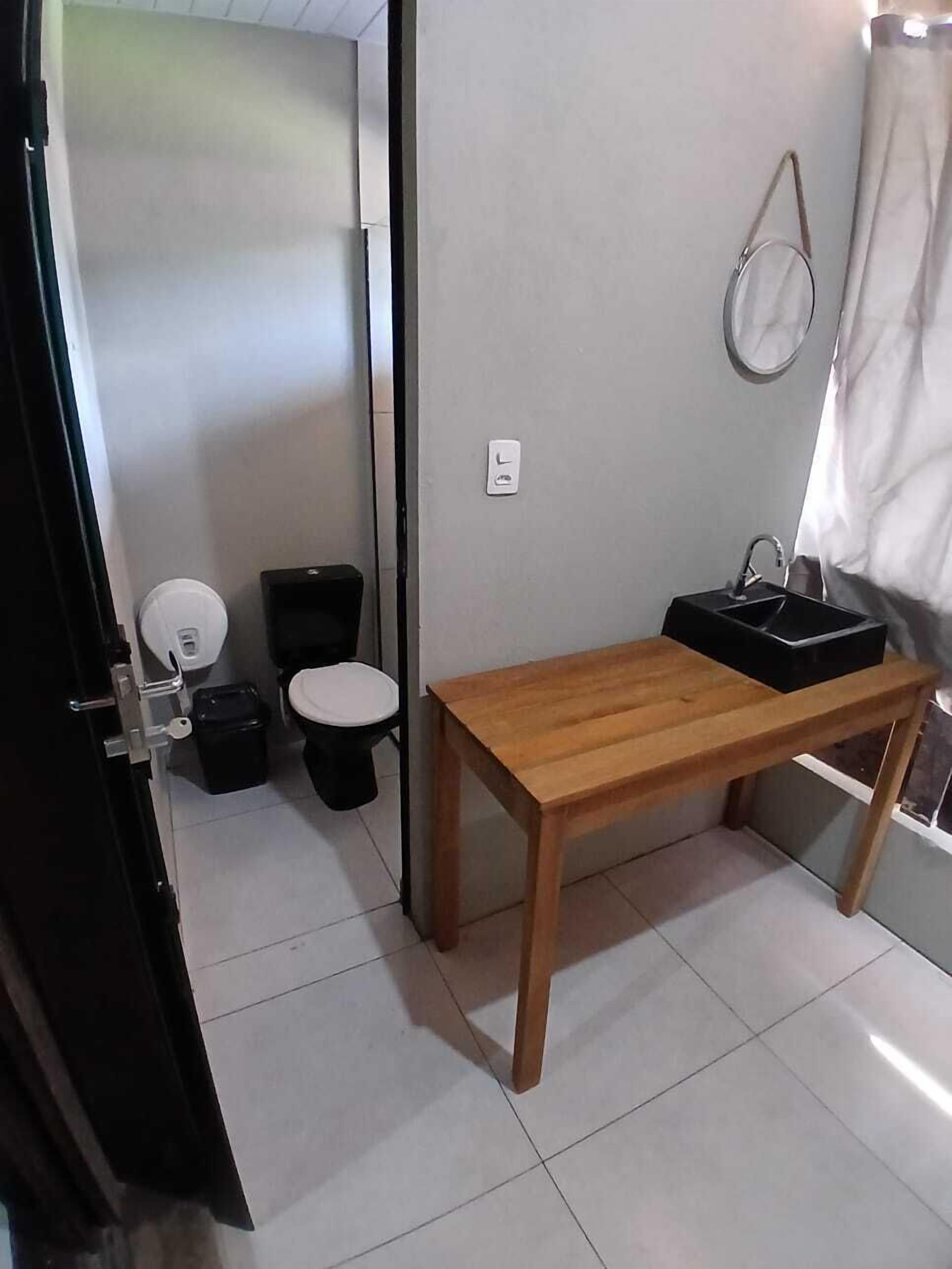 A small, compact bathroom with a toilet, sink, and a wooden bench.