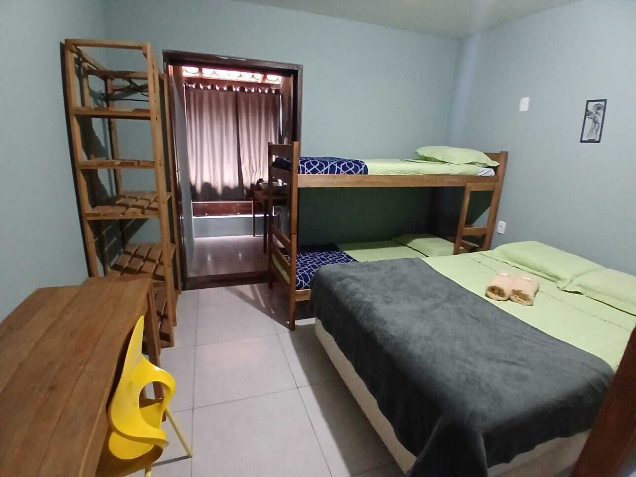 Une chambre de dortoir avec des lits superposés, un bureau en bois, une chaise et une porte donnant sur un balcon.