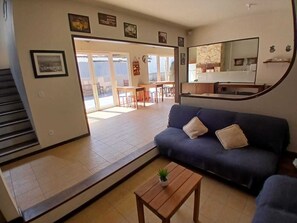 A living room with a sofa, a coffee table, and a staircase leading to a balcony. - Maga Inn House - Centro (Blumenau)