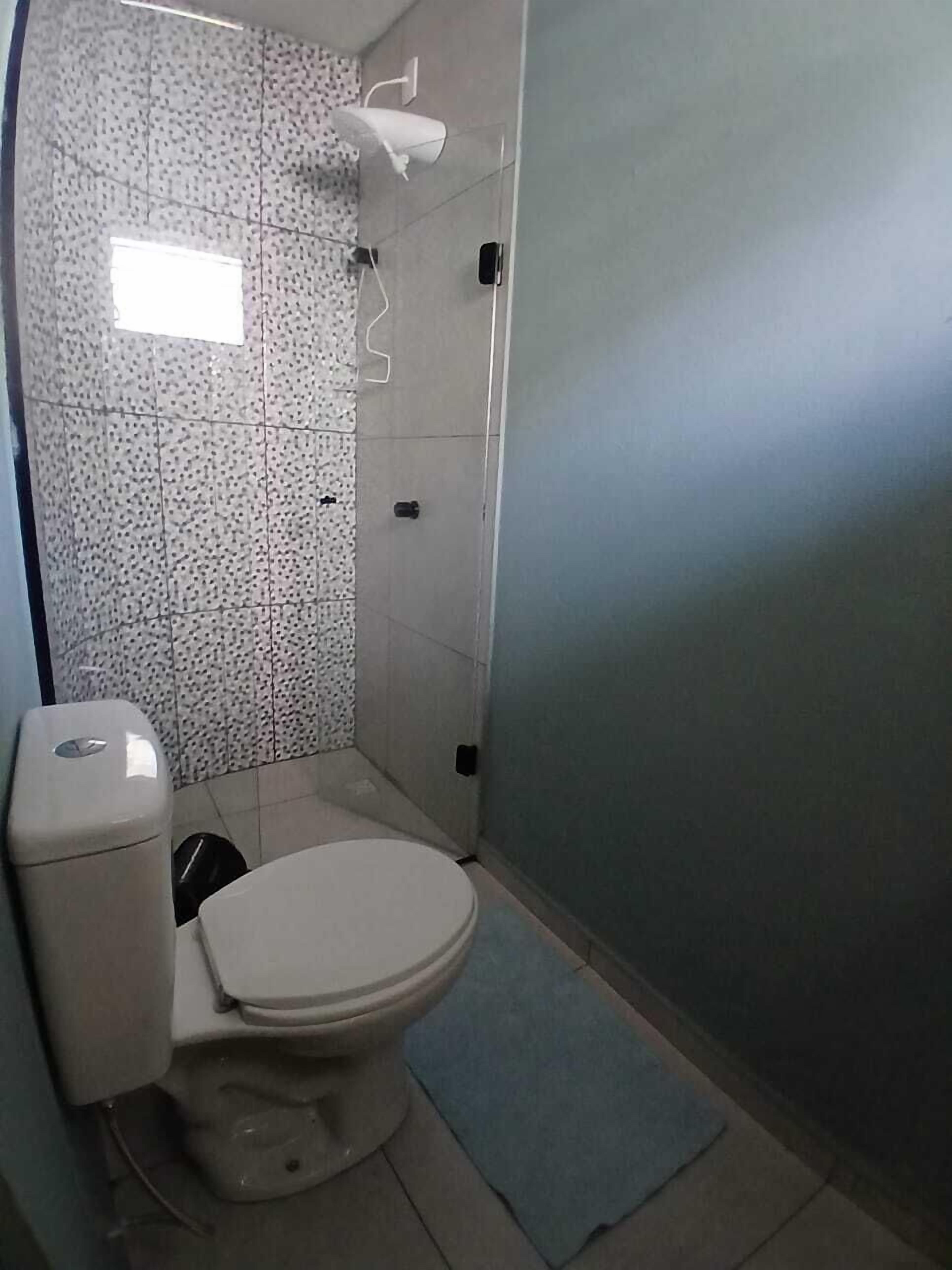 A small bathroom with a toilet, a shower, and a sink.