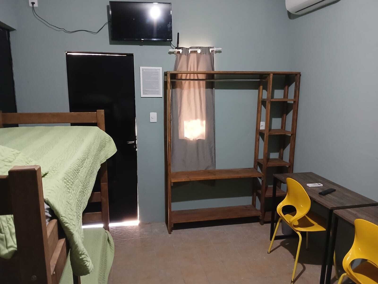 Un dormitorio con una cama, un escritorio, una silla, un televisor y un armario.