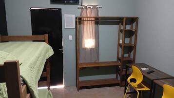 Un dormitorio con una cama, un escritorio, una silla, un televisor y un armario.