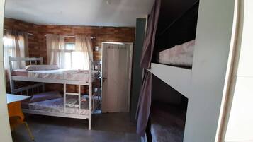 Un dormitorio con literas, una mesita pequeña y una puerta.