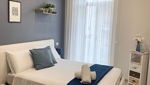 Un dormitorio moderno con cama, mesita de noche, ventana con cortinas y aire acondicionado de pared.
