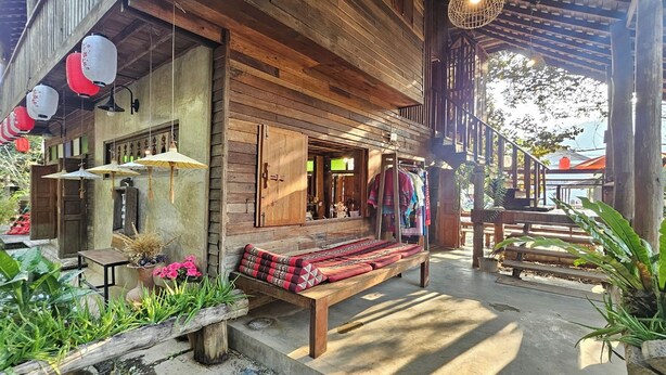 A wooden building with a bench and potted plants outside.