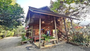 A rustic wooden building with a porch, surrounded by greenery.