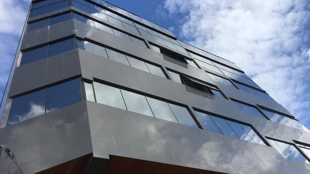 A modern building with a glass facade and a wooden lower section. - Village Plaza Hotel (Barbacena)