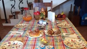 A dining table set with various food items and utensils, a glass bowl of baked goods, and a staircase in the background. - Il Ficodindia (Santa Ninfa)
