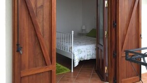 A room with a bed, a small table, and a door with a rustic design. - Il Ficodindia (Santa Ninfa)