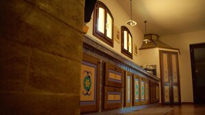 A hallway with wooden doors, a tiled floor, and a hanging light fixture. - Il Ficodindia (Santa Ninfa)