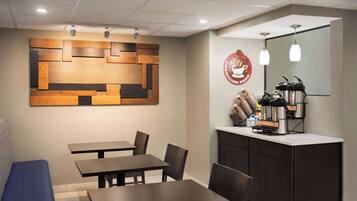 Een modern café met een wand van hout, een koffiehoek en zitmogelijkheden.