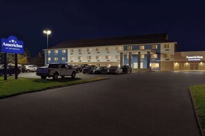 Un hôtel doté d’un parking, d’une enseigne indiquant « AmericInn by Wyndham », et d’un bâtiment avec de nombreuses fenêtres et un toit plat.