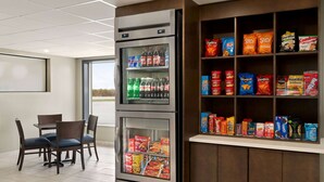 Máquina automática de sumos e snacks, zona de estar com cadeiras e janela com vista.