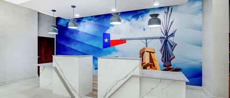 A reception area with marble counters, pendant lighting, and a mural of the Texas flag.