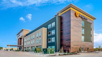 A modern hotel with a prominent 'La Quinta' sign, multiple floors, and a covered entrance area.