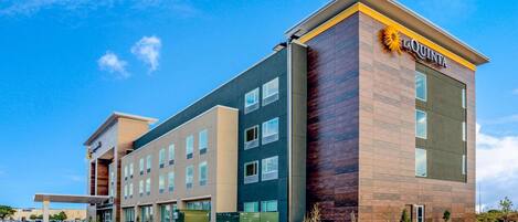 A modern hotel with a prominent 'La Quinta' sign, multiple floors, and a covered entrance area.