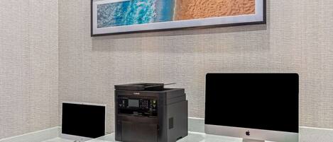 A workspace with a desktop computer, a printer, and a monitor on a desk.