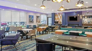 Un moderno vestíbulo de hotel con zonas de estar, un bar y una gran pantalla de televisión.