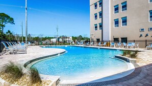 Una piscina con sillas de descanso y un edificio al fondo.