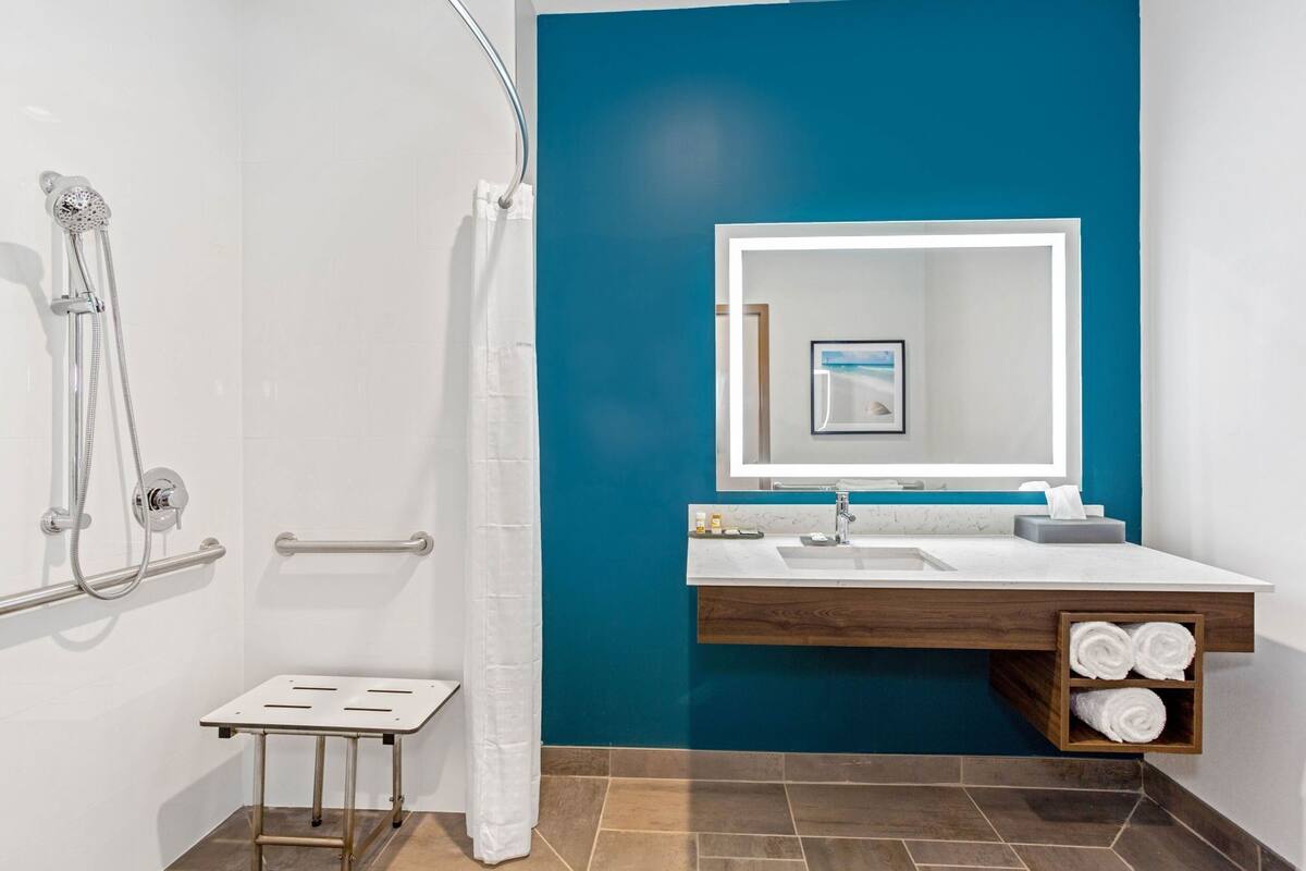 A bathroom with a shower, a sink with a mirror, and a towel rack.