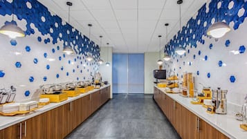 A modern kitchen with a long counter, hexagonal blue tiles on the walls, and pendant lighting.