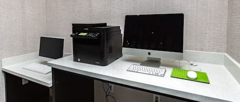 Uma mesa de escritório moderna com um computador, impressora, teclado, rato e monitor.
