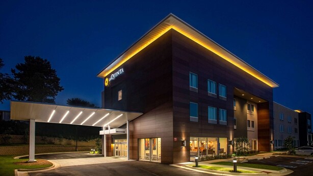 Een modern hotel met een overdekte ingang, meerdere verdiepingen en een goed verlichte gevel.