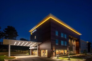 Un hotel moderno con entrada cubierta, varios pisos y fachada bien iluminada.