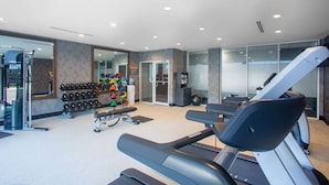 Een moderne sportschool met loopbanden, gewichten en diverse fitnessapparaten.