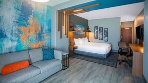Een moderne hotelkamer met een groot bed, een slaapbank, een bureau en een televisie.